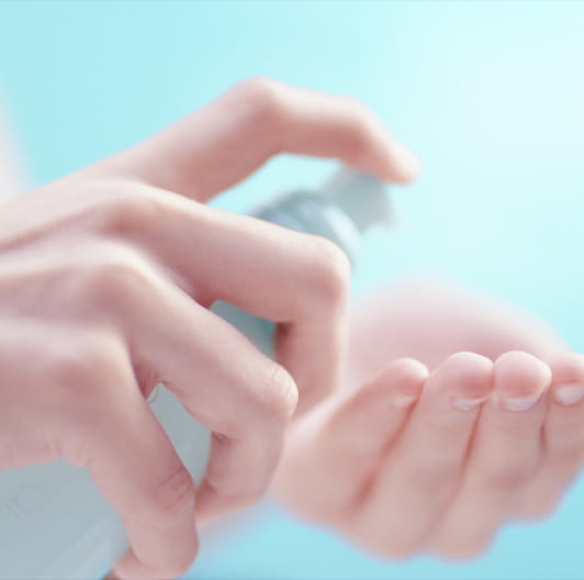 化粧水をつけようと、手にプッシュしている女性の手の画像