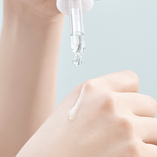 スポイトから肌に美容液を垂らし、水滴が乗っている様子の画像